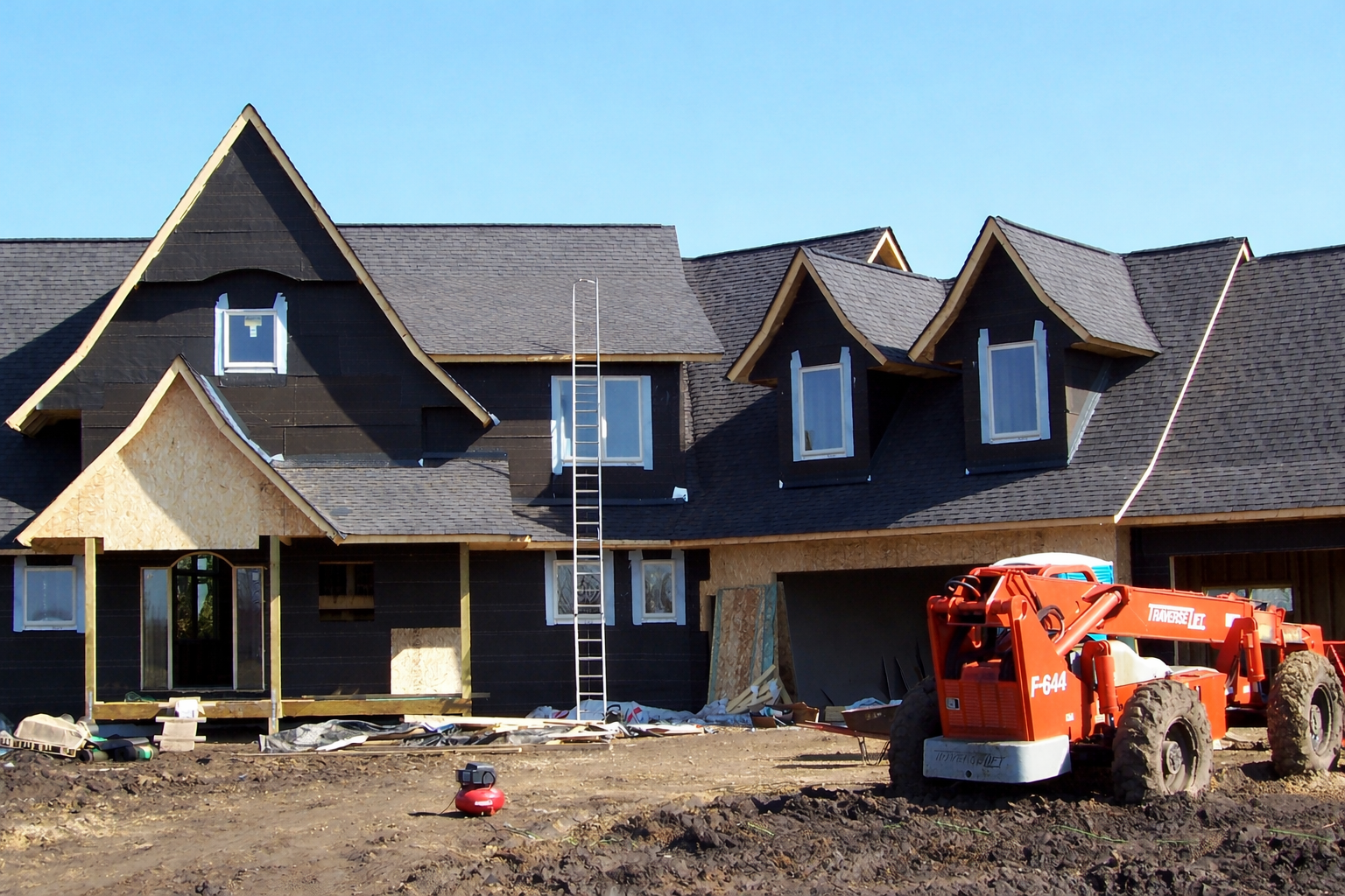 New custom home construction in Ham Lake, MN — Northern Forge Construction with boom lift and exterior framing in progress